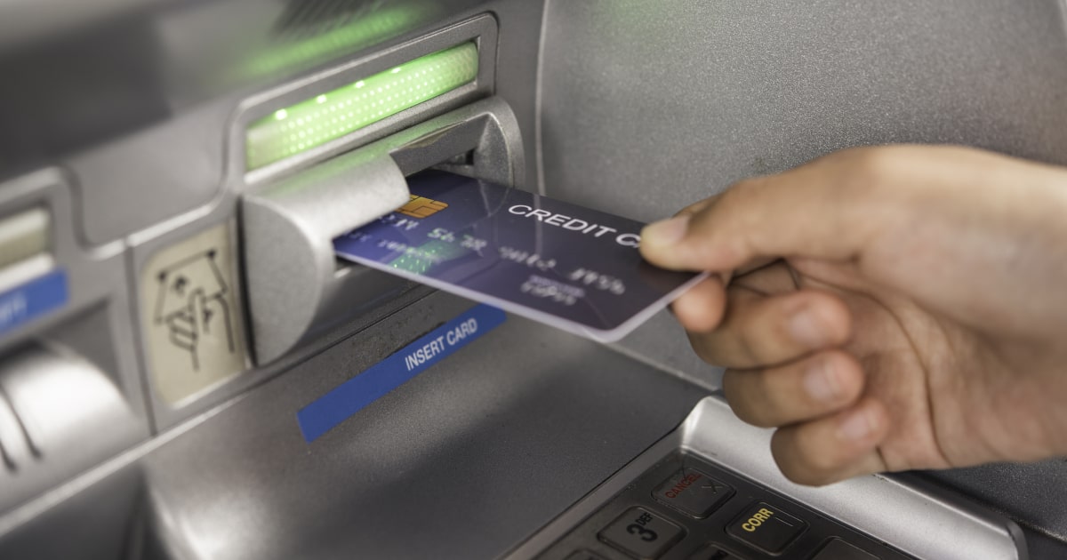 Obrazek przedstawia wkładanie karty do bankomatu, strona z numerem karty zwrócona do góry